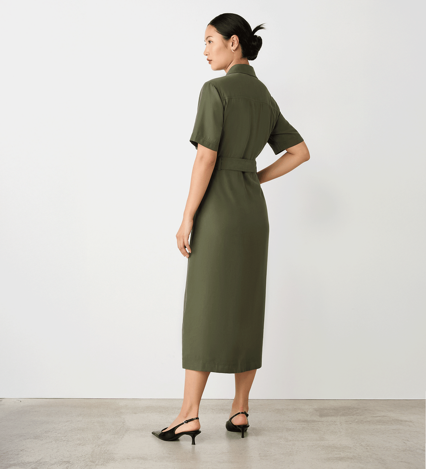 Full body back view of a model wearing the Cassidy Khaki Midi Shirt Dress facing side-on.