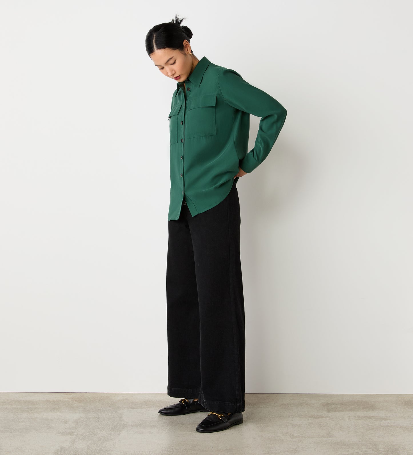 Full body view of a model wearing the Nicola Dark Green Utility Shirt untucked, facing side-on.