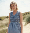 Woman wearing Hadlee Navy Cotton Gingham Shirred Bodice Sleeveless Midi Dress on a beach.