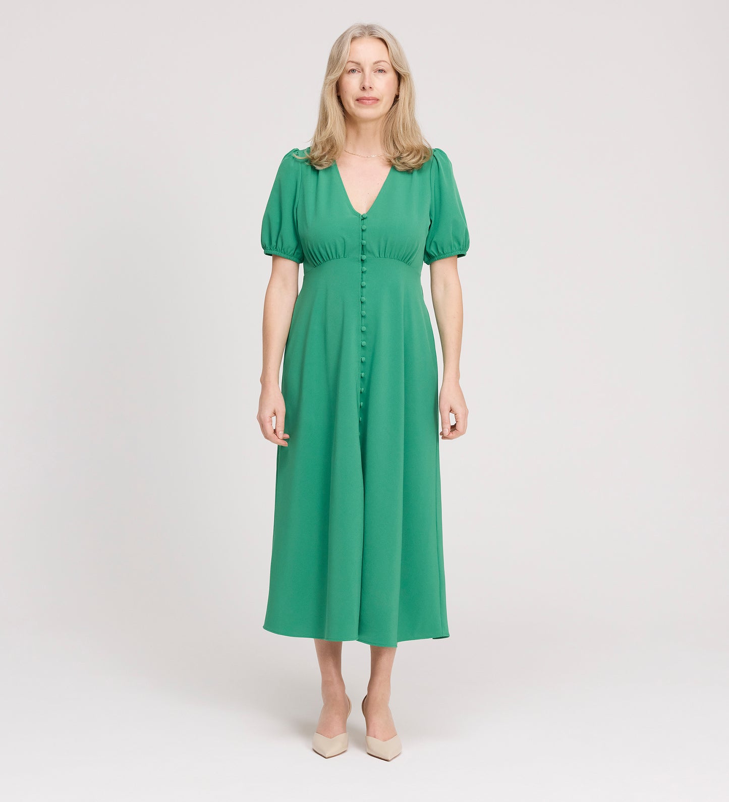 A woman with long, light hair wears the Robyn Green Button Through Midi Dress and beige heels, standing facing the camera against a plain white background.