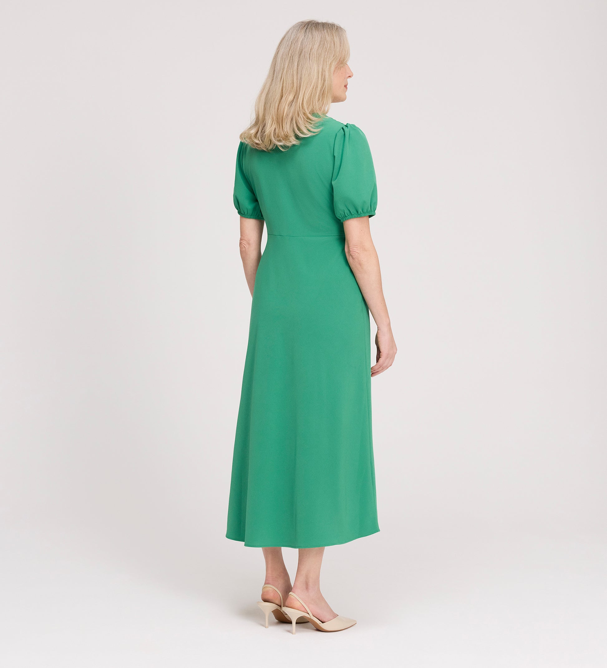 A woman with blonde hair wears the Robyn Green Button Through Midi Dress with puff sleeves and beige heels, standing against a plain white background and looking to the side.