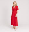 A woman with light hair wears the Robyn Red Button Through Midi Dress with short sleeves and cream flats, standing against a plain light background.