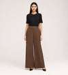 A woman stands against a plain background, wearing a black short-sleeve top, black pointed-toe shoes, and the Addie Mushroom Gaberdine Twill Wide Leg Trousers. She faces forward with a neutral expression and her arms at her sides.