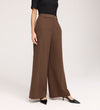 A person wearing a black short-sleeve top, Addie Mushroom Gaberdine Twill Wide Leg Trousers, and black pointed-toe heels stands against a plain light background.