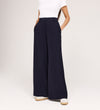 Only the lower half of a person is visible, wearing a white short-sleeve top and Addie Navy Gaberdine Twill Wide Leg Trousers with hands in pockets, standing against a white background.