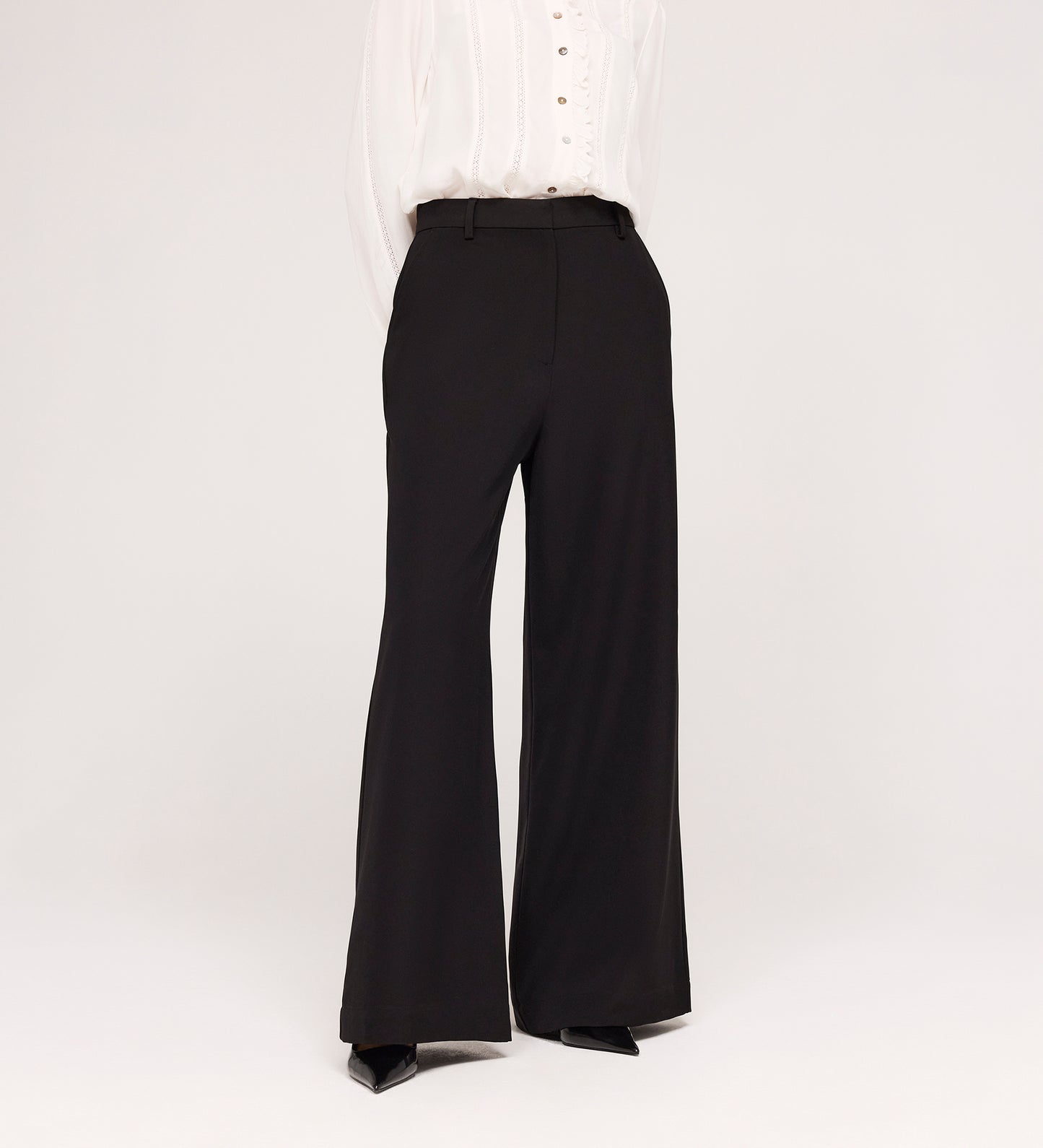 A person models the Addie Black Gaberdine Twill Wide Leg Trousers with a white blouse against a plain white background, their head not shown in the image.
