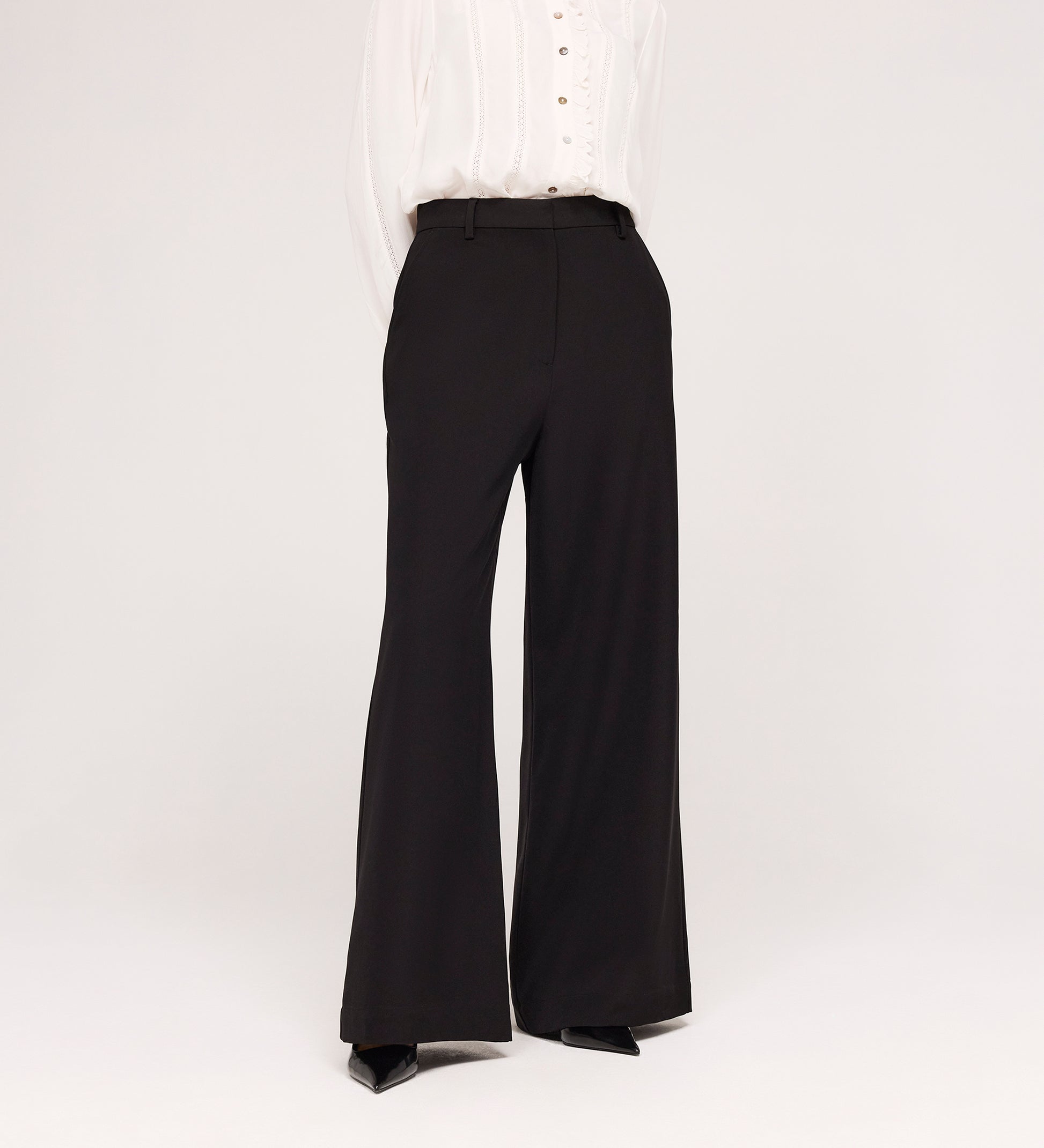 A person models the Addie Black Gaberdine Twill Wide Leg Trousers with a white blouse against a plain white background, their head not shown in the image.