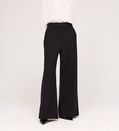 A person models the Addie Black Gaberdine Twill Wide Leg Trousers with a white blouse against a plain white background, their head not shown in the image.