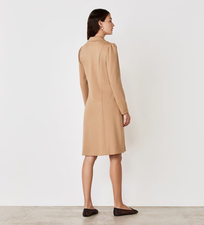 A woman stands with her back to the camera, wearing the Bethany Camel Ponte Jersey Knee Length Dress and black flats, set against a plain white background.