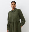 A woman confidently stands against a plain white background wearing the Callie Khaki Corduroy Midi Dress, featuring chest pockets and a front zipper.