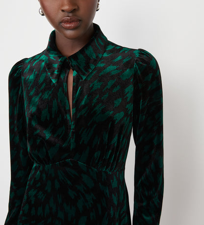 A woman wears the Capri Green Animal Knee Length Dress—a dark green and black patterned velvet dress with long sleeves, pointed collar, empire waist, and keyhole cutout—perfect for parties. The background is plain white.