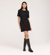 A woman stands against a plain background, wearing the Cherry Black Short Sleeve Jersey T-Shirt with a relaxed fit, paired with a black mini skirt and knee-high black boots.