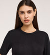 A woman with long, straight brown hair wears the Cherry Black Short Sleeve Jersey T-Shirt and small hoop earrings, standing against a plain light background and looking directly at the camera with a neutral expression.
