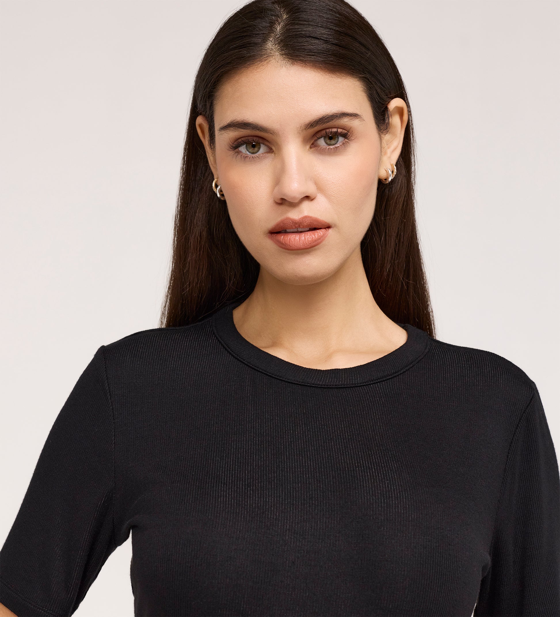 A woman with long, straight brown hair wears the Cherry Black Short Sleeve Jersey T-Shirt and small hoop earrings, standing against a plain light background and looking directly at the camera with a neutral expression.