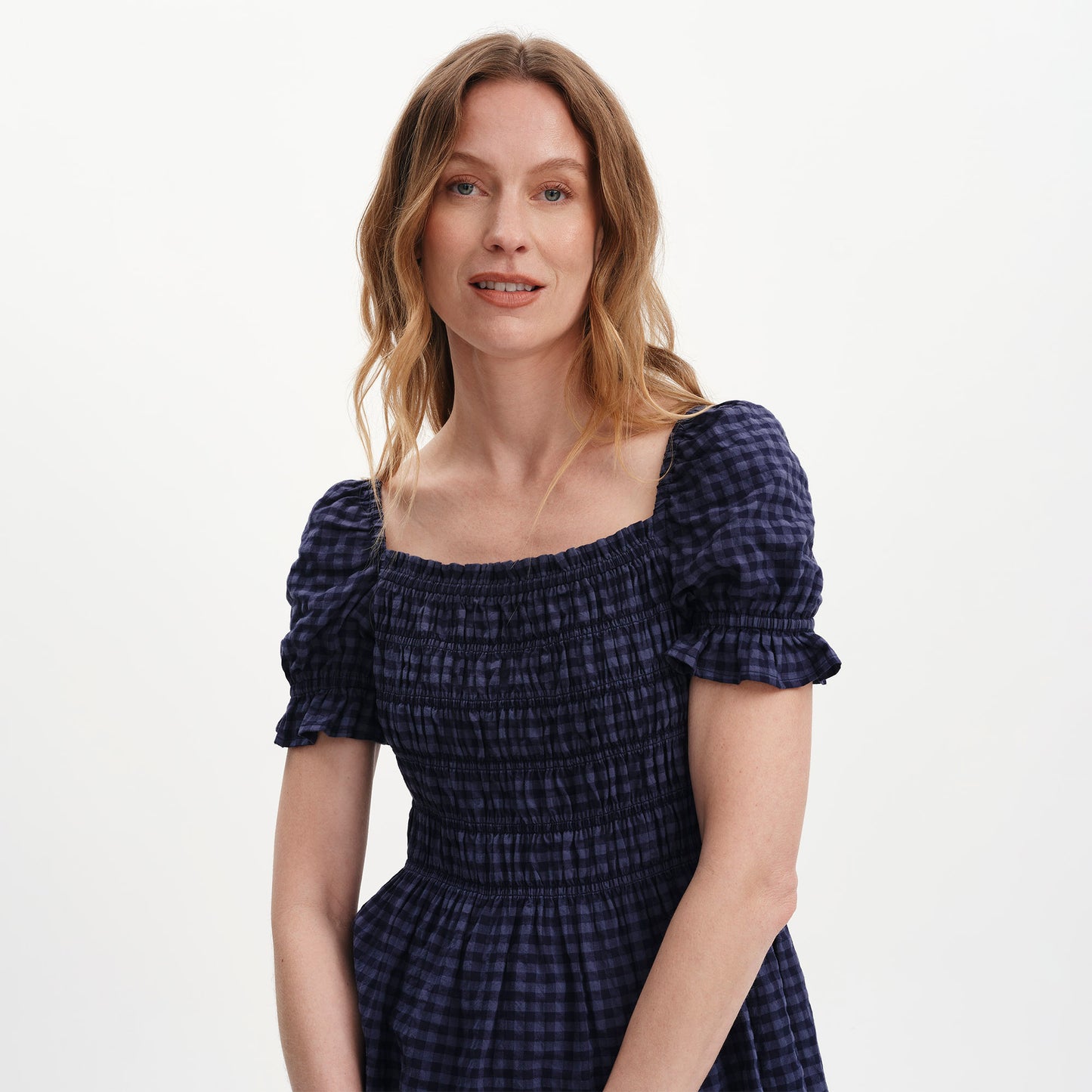 Woman wearing Cynthia Navy Gingham Seersucker Shirred Puff Sleeve Top with puff sleeves on a white background