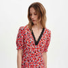 Woman wearing Elish Red Ditsy Lace Trim Puff Sleeve Midi Dress with black lace trim on a white background