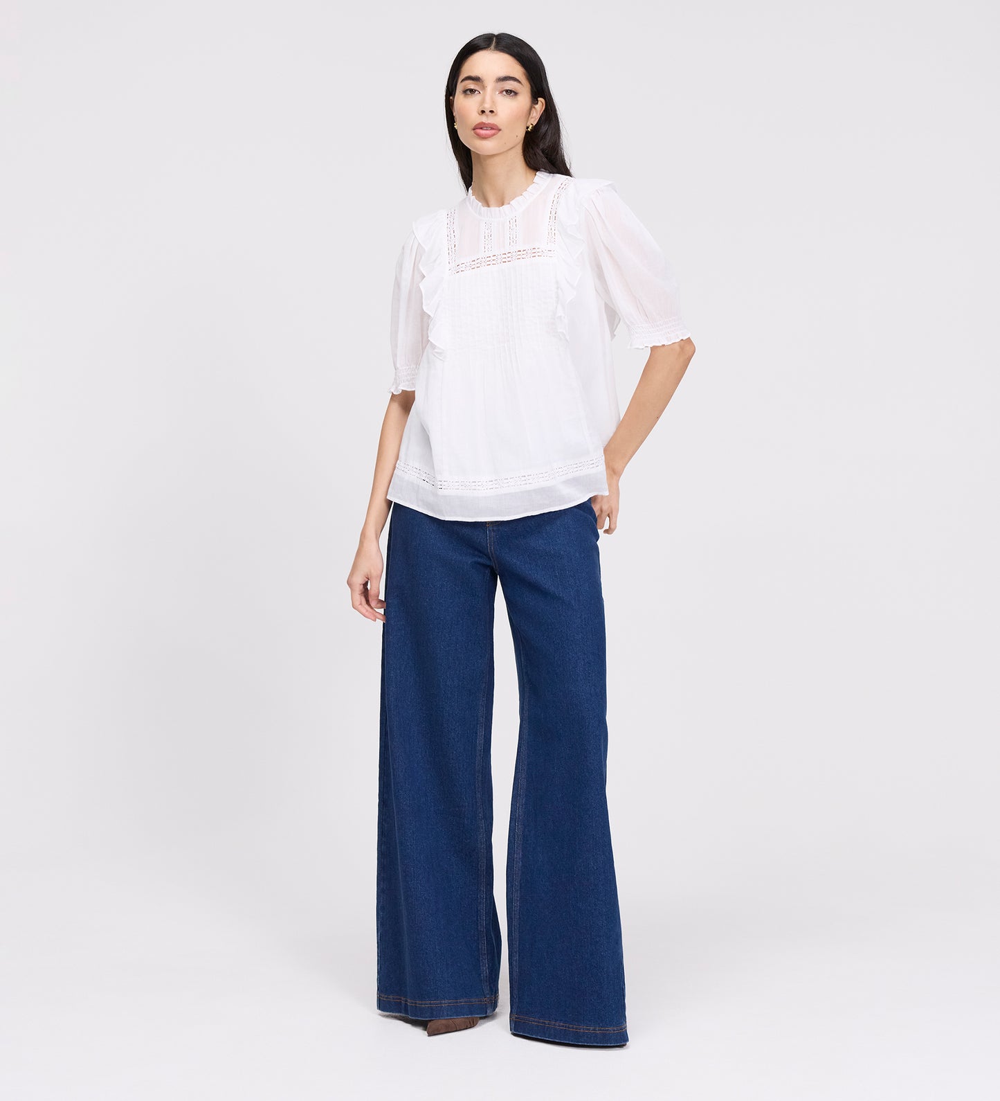 Woman wearing Jolin White Lace Cotton Puff Sleeve Top and blue pants on a white background