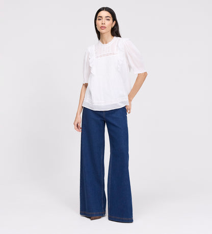 Woman wearing Jolin White Lace Cotton Puff Sleeve Top and blue pants on a white background
