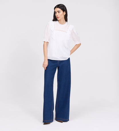 Woman wearing Jolin White Lace Cotton Puff Sleeve Top and blue pants on a white background