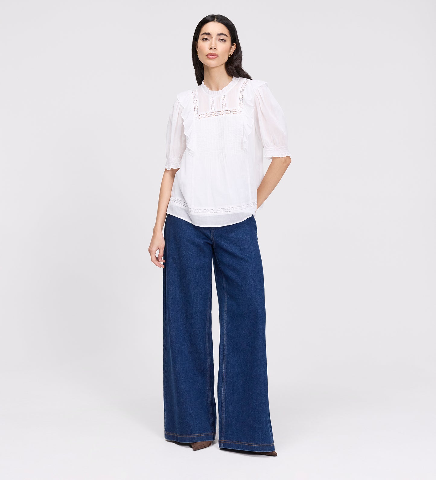 Woman wearing Jolin White Lace Cotton Puff Sleeve Top and blue jeans on a white background