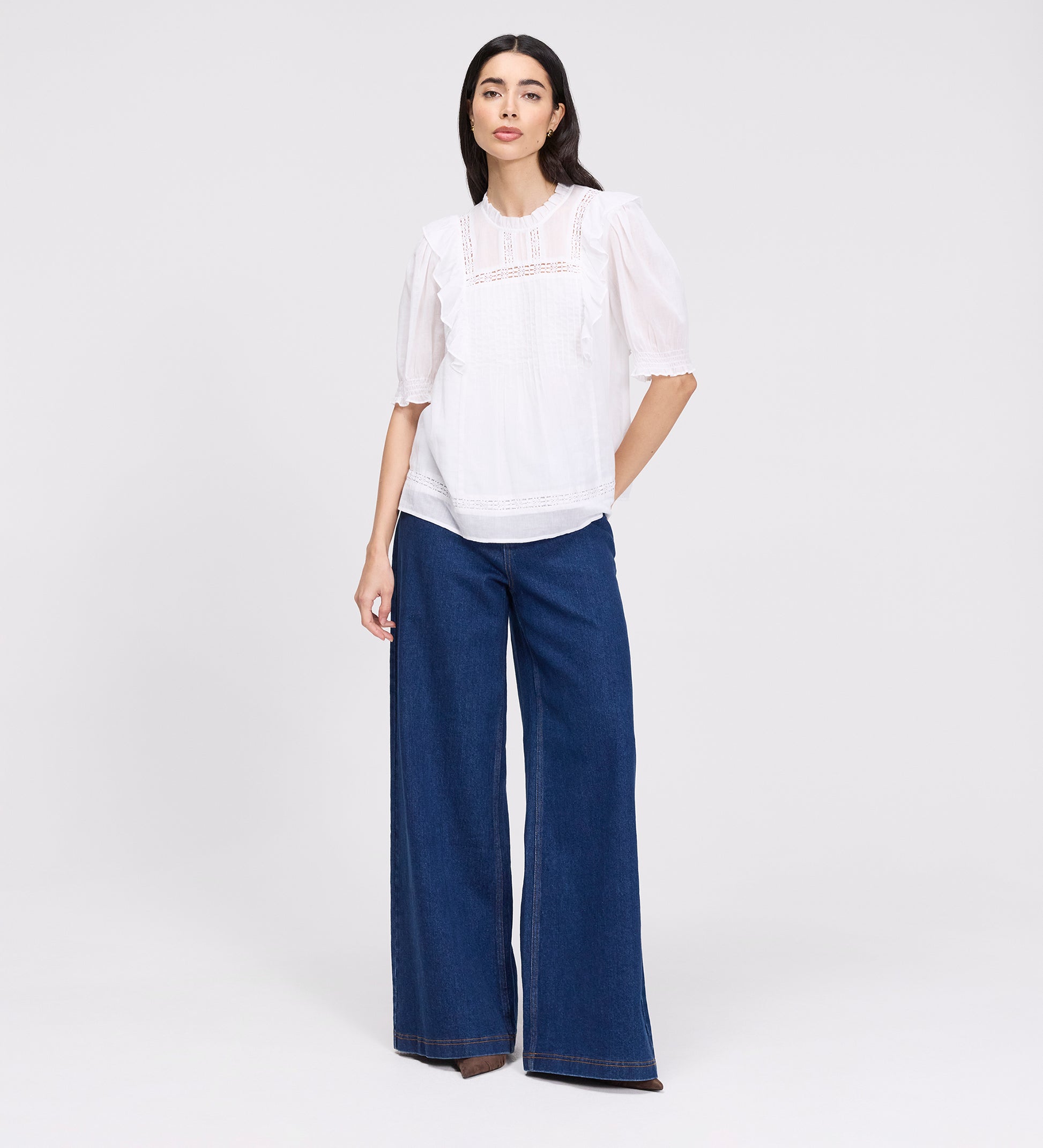 Woman wearing Jolin White Lace Cotton Puff Sleeve Top and blue jeans on a white background