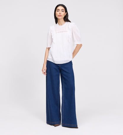 Woman wearing Jolin White Lace Cotton Puff Sleeve Top and blue jeans on a white background