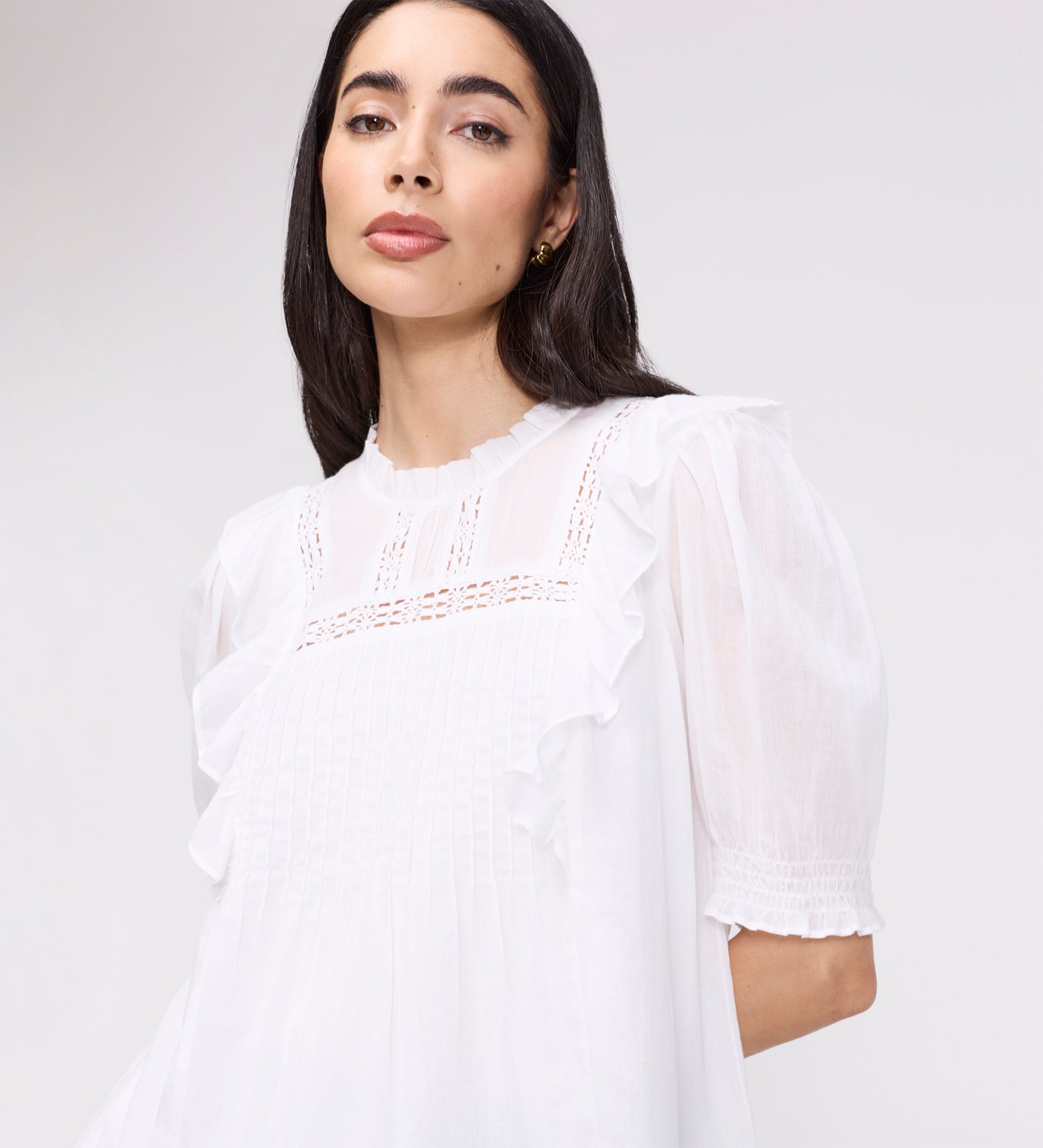 Woman wearing Jolin White Lace Cotton Puff Sleeve Top with lace details on a plain background