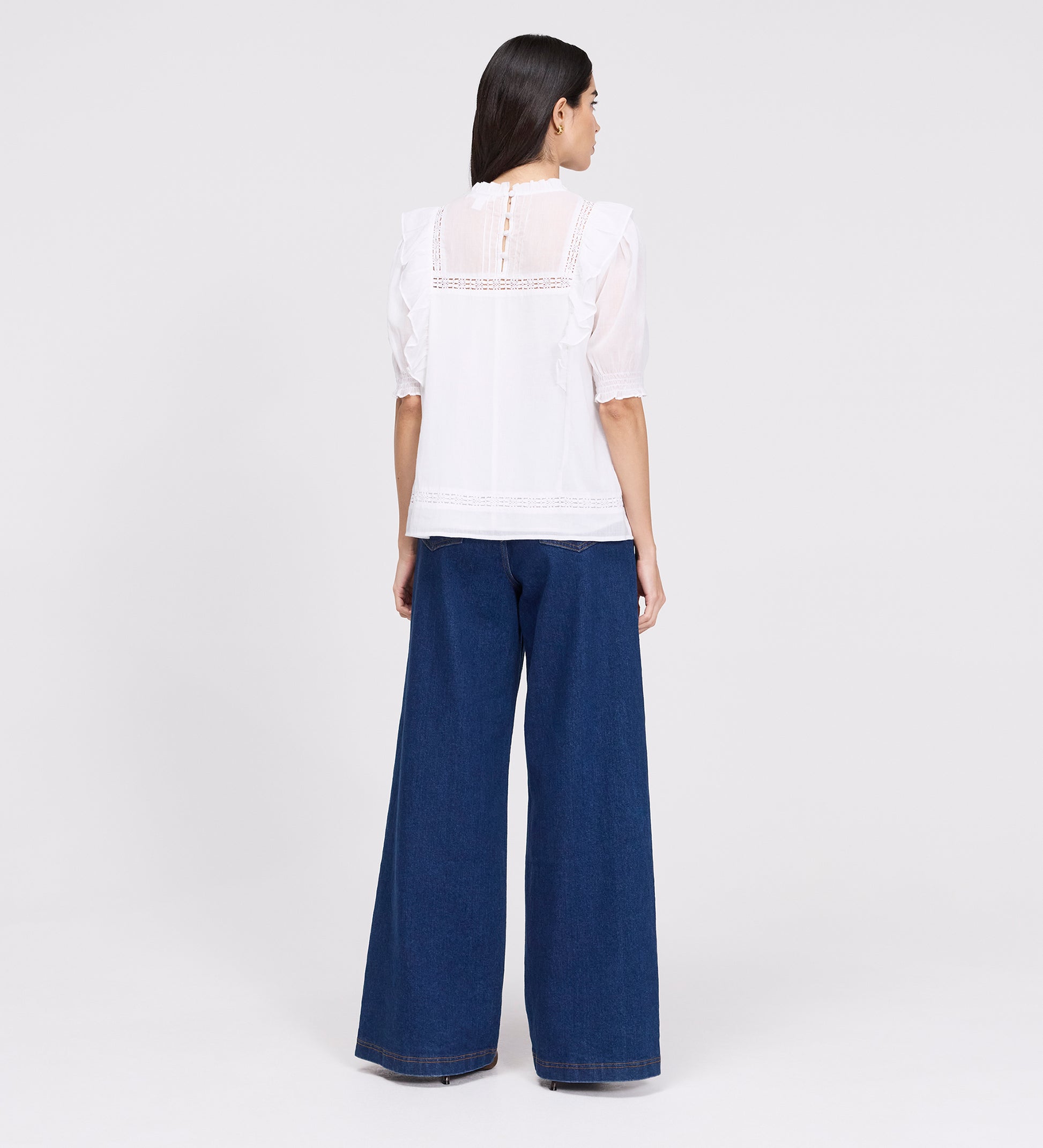 Woman wearing Jolin White Lace Cotton Puff Sleeve Top and blue jeans on a white background