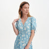 Woman wearing Margot Blue Ditsy Puff Sleeve Button Through Midi Dress on a light gray background