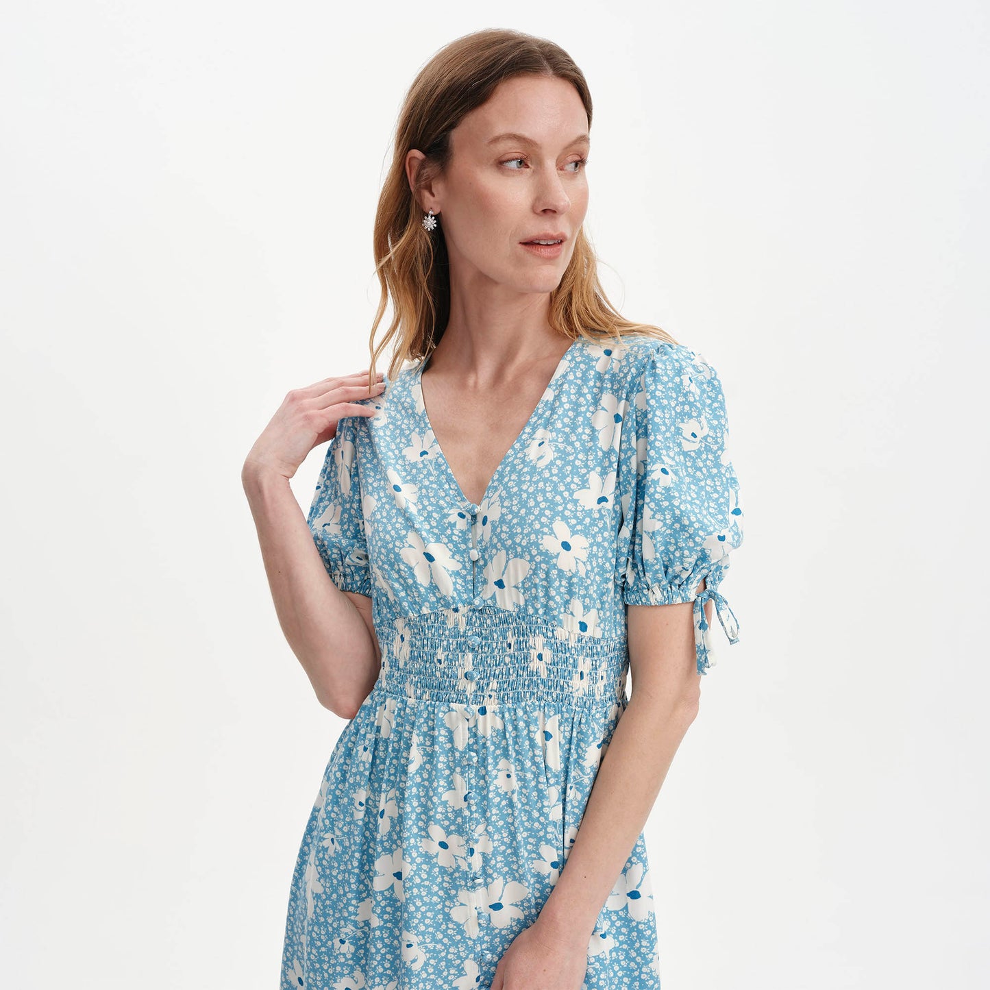 Woman wearing Margot Blue Ditsy Puff Sleeve Button Through Midi Dress on a light gray background