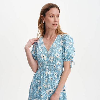 Woman wearing Margot Blue Ditsy Puff Sleeve Button Through Midi Dress on a light gray background