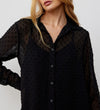 A woman models the Janette Black Chiffon Blouse With Detachable Cami, featuring sheer fabric with a textured spot design, against a plain light background. Her face is partially out of frame.
