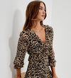 A woman wearing Veronica Natural Animal Ruffle Empire Waist Midi Dress, photographed against a plain white wall.