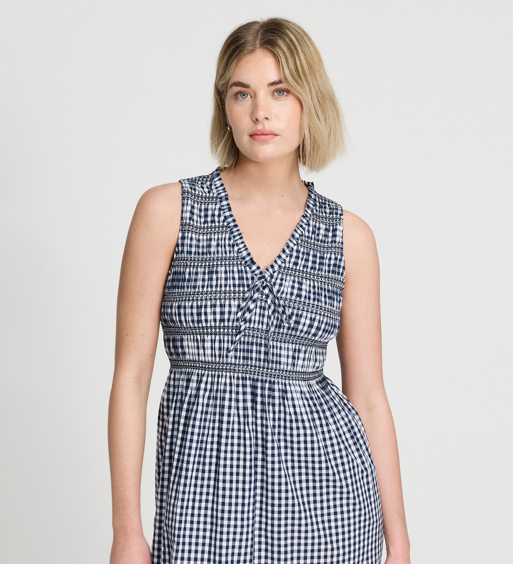 Woman wearing Hadlee Navy Cotton Gingham Shirred Bodice Sleeveless Midi Dress against a plain background