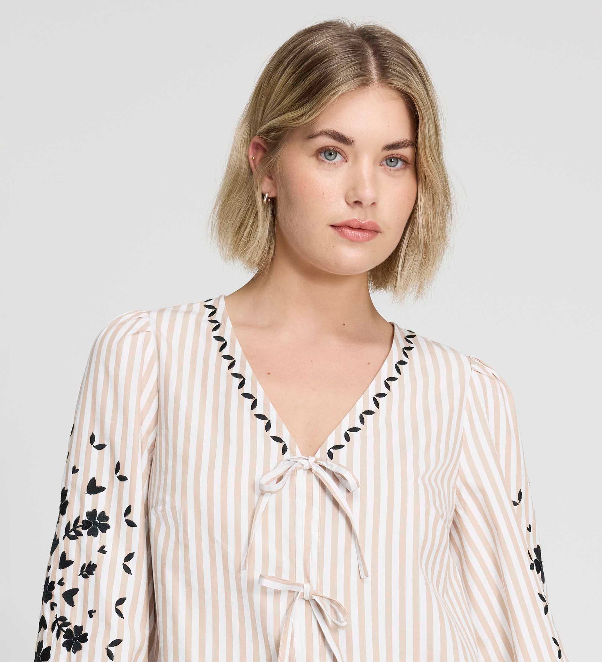 Woman wearing Karlee Neutral Stripe Embroidered Cotton Tie Front Blouse on a plain background