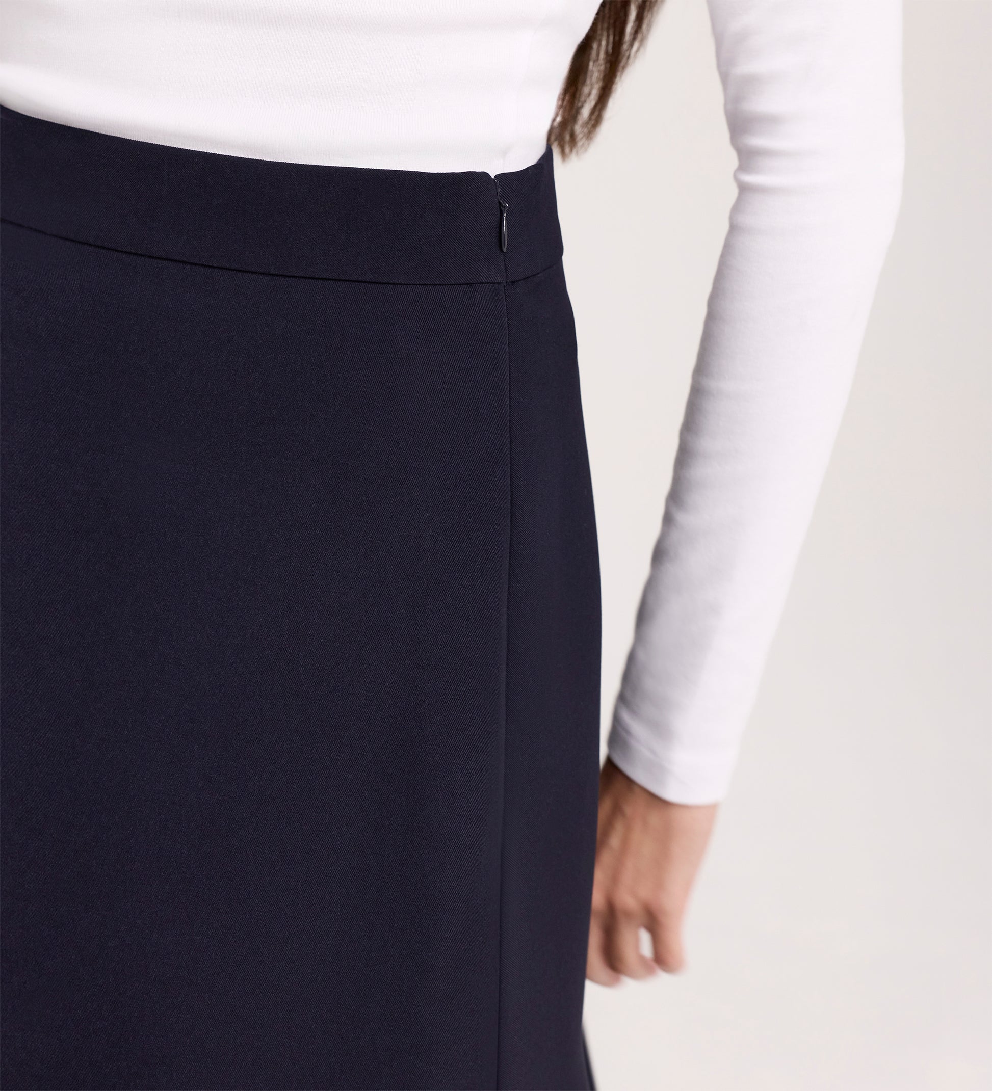 A person is shown from the back and waist down wearing a white long-sleeve shirt and the Ramona Navy Rich Crepe Midi Skirt, with one arm relaxed by their side.