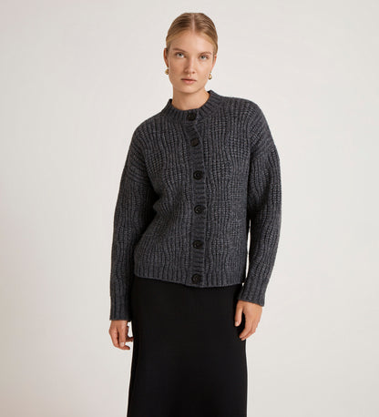 Woman wearing a dark gray textured sweater with black buttons on a light background