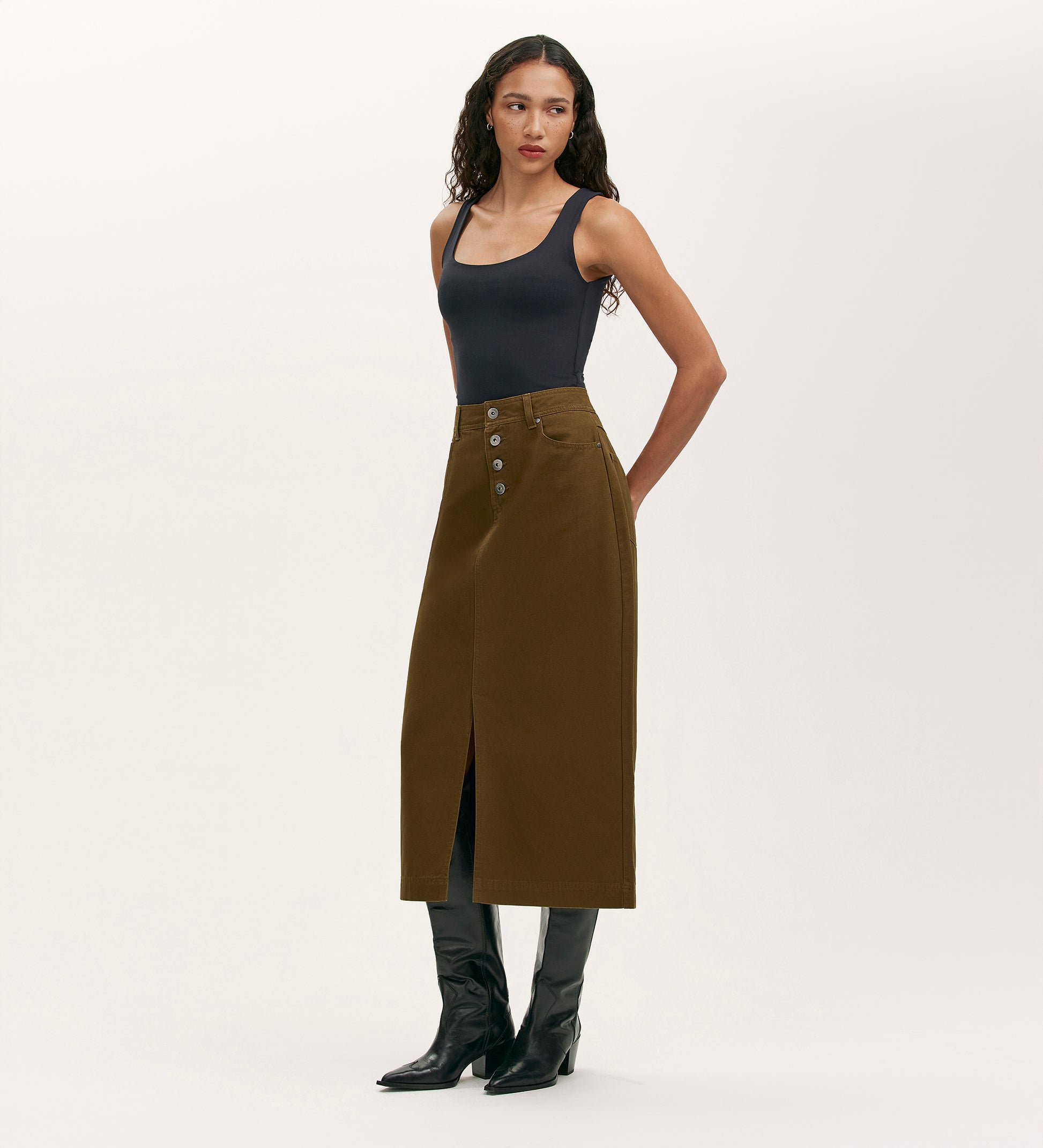 A woman wears the Beth Khaki Canvas Midi Skirt, featuring a high waistband.