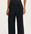 A woman wearing the Caryl Black Ponte Jersey Wide Leg Trouser, featuring pintuck detailing and an elasticated waistband.