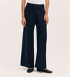 Someone is wearing Caryl Navy Ponte Jersey Wide Leg Trousers with an elasticated waistband, a white top, and black flats. The cropped image captures only the lower torso and legs against a plain light background.