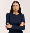 A woman with long wavy brown hair stands confidently against a plain light background, wearing the Eva Navy Ponte Jersey Short Dress featuring princess seams.