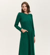 A woman with shoulder-length brown hair wears the Felice Bottle Green Ponte Jersey Midi Dress, featuring long sleeves, pockets, and a tailored silhouette against a plain light background.