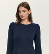 A woman with straight brown hair models the Felice Navy Ponte Jersey Midi Dress, featuring long sleeves, slight shoulder gathers, and a tailored silhouette, against a plain light background.