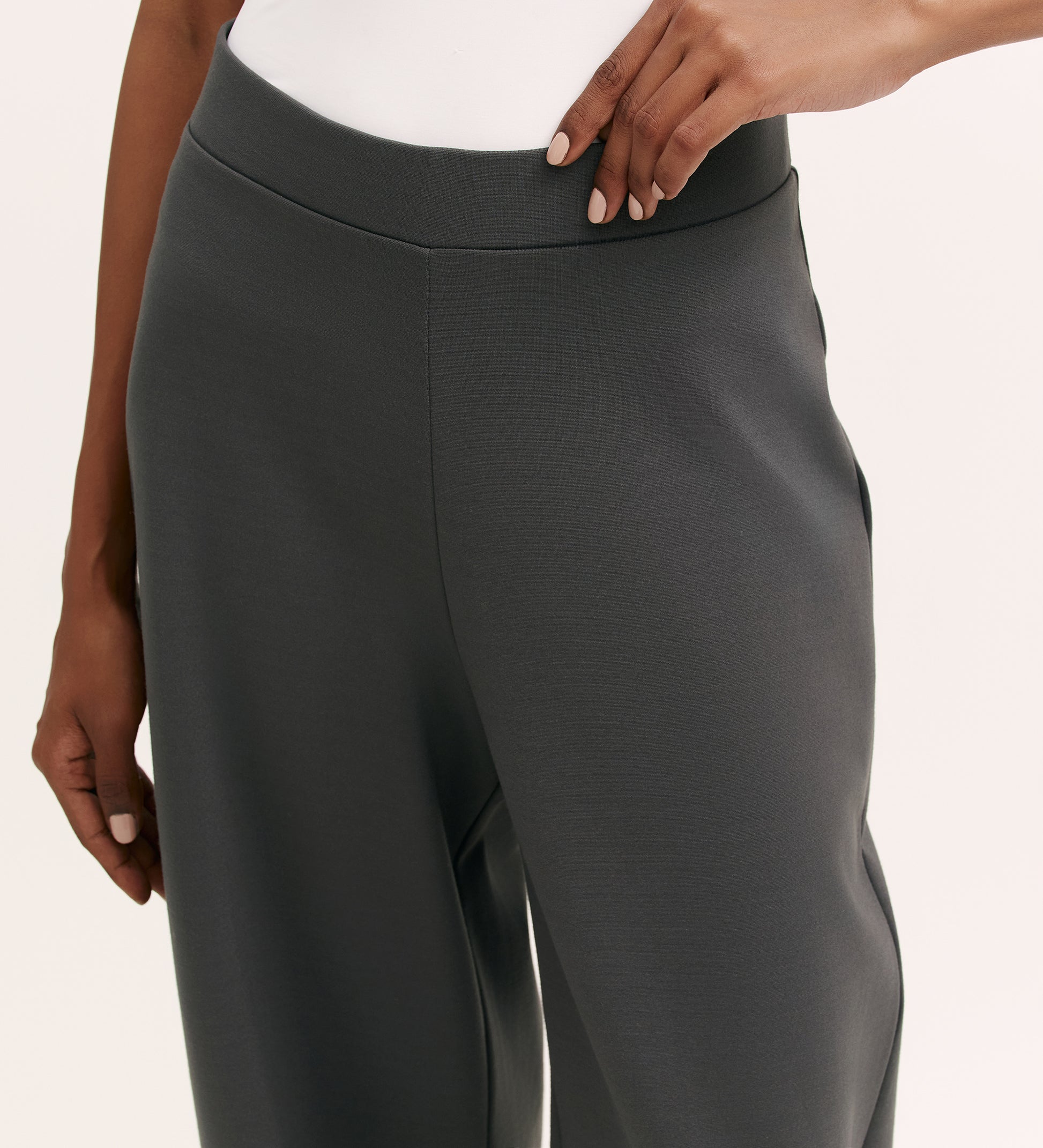 A person wears Kenzie Charcoal Ponte Jersey Wide Leg Trousers with an elasticated waistband and a white top, posing with one hand on their hip against a light background.