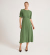 A woman in the Mela Green Chiffon Midi Tea Dress stands against a plain white background. Her hair is pulled back and she wears black pointed-toe heels.