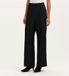 A person wears the Nellie Black Canvas Wide Leg Trousers, featuring high-waisted and side button details, paired with a white top and black heeled boots against a plain light background—showcasing a versatile wardrobe staple.