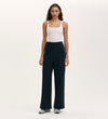 A woman faces forward against a plain light background wearing a white tank top, Nellie Navy Canvas Wide Leg Trousers with side button details, and light blue sneakers.