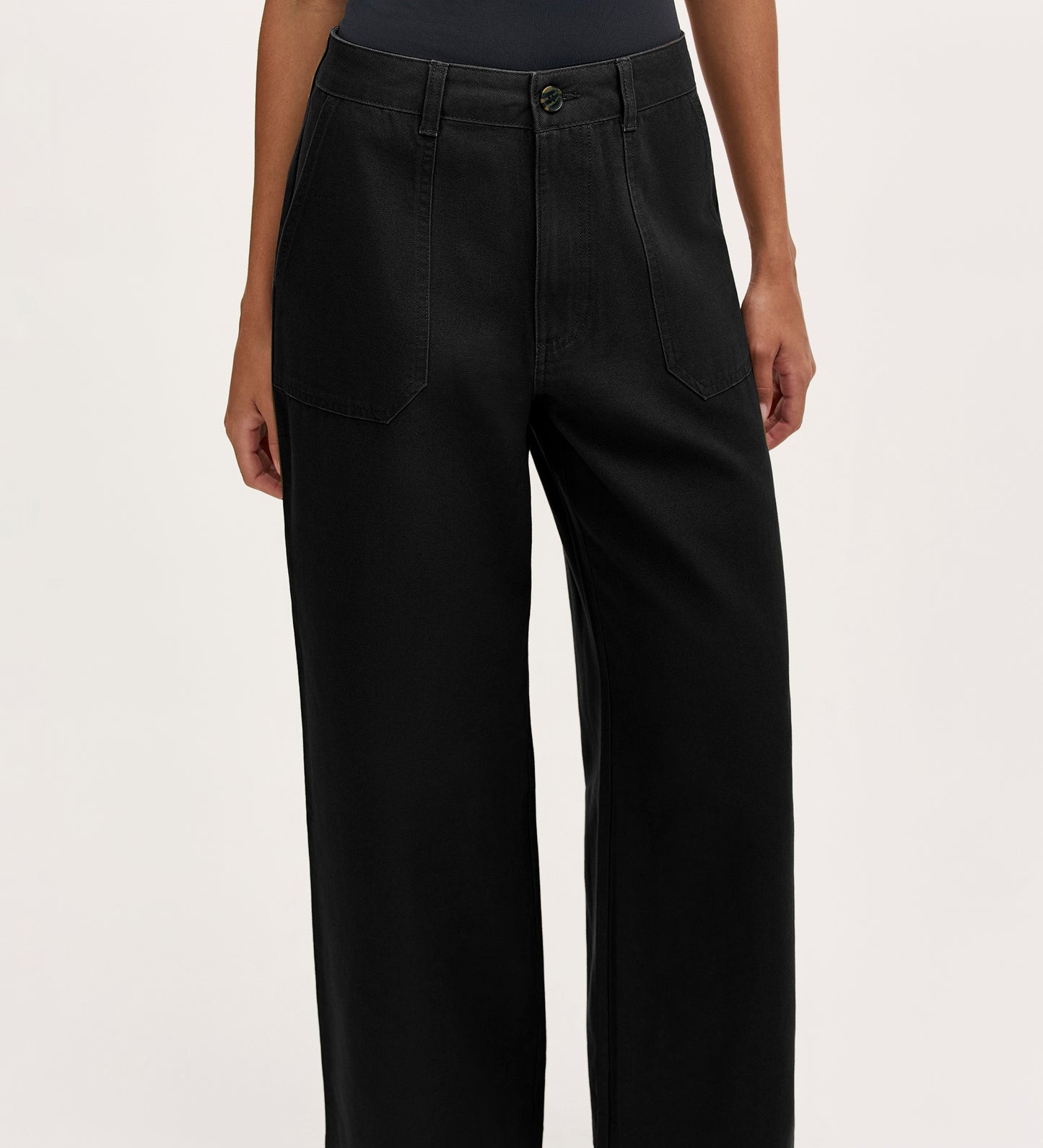 A person models the Olive Black Canvas Wide Leg Trousers—high-waisted with front pockets—in an elevated casual style, shown from waist to ankles against a plain light background.