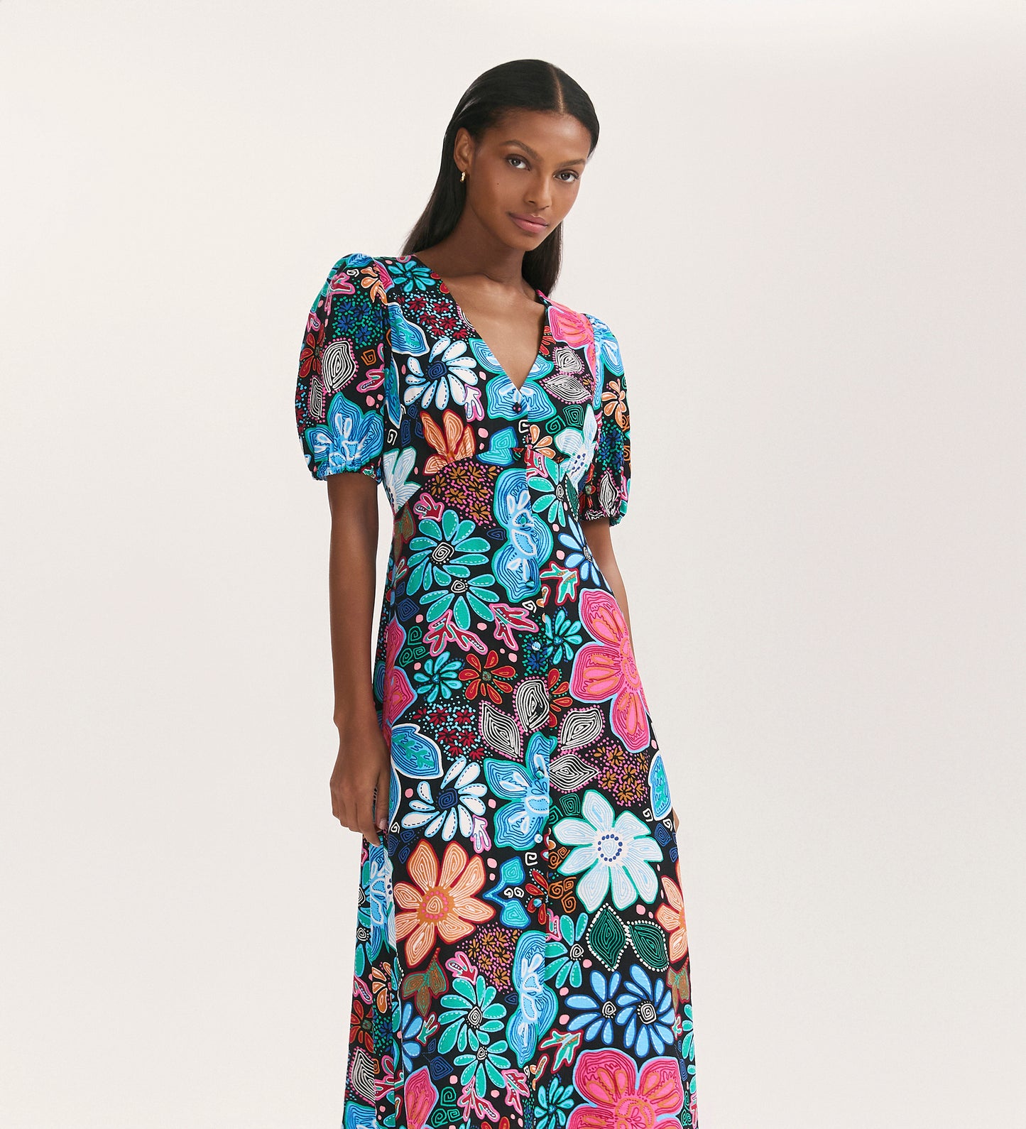 A woman models the Sarah Blue Floral Crepe Midi Dress, featuring short sleeves and a button-through front, against a plain white background.