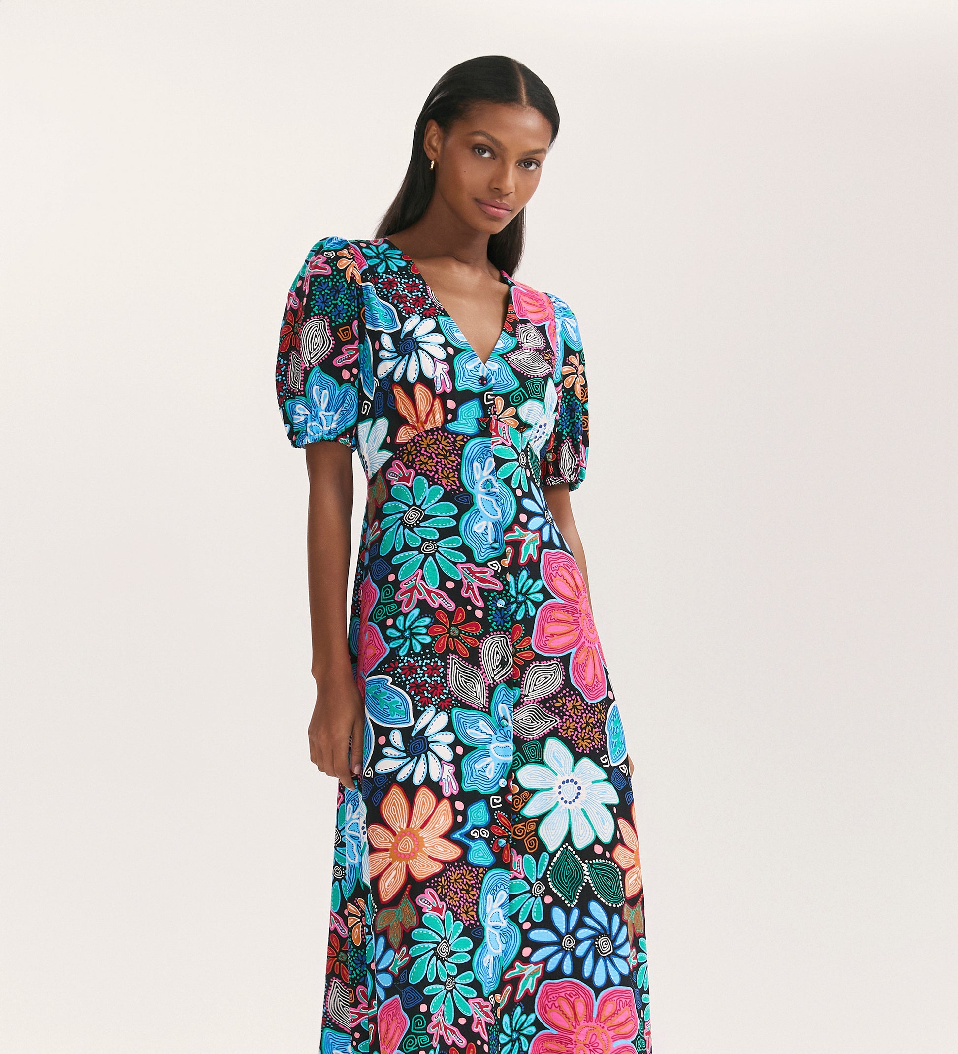 A woman models the Sarah Blue Floral Crepe Midi Dress, featuring short sleeves and a button-through front, against a plain white background.